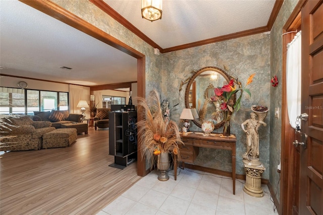 entryway with ornamental molding, light hardwood / wood-style flooring, and a textured ceiling