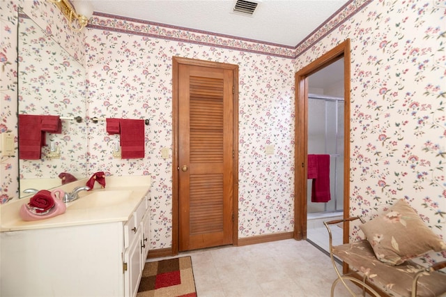 bathroom with vanity, a textured ceiling, and a shower with shower door