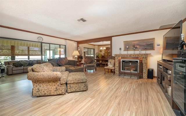 living room featuring ornamental molding, an inviting chandelier, a textured ceiling, and light hardwood / wood-style floors