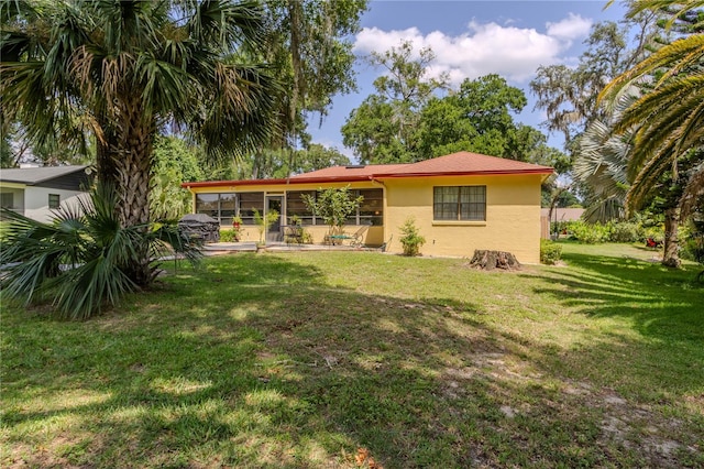 back of property featuring a lawn and a sunroom