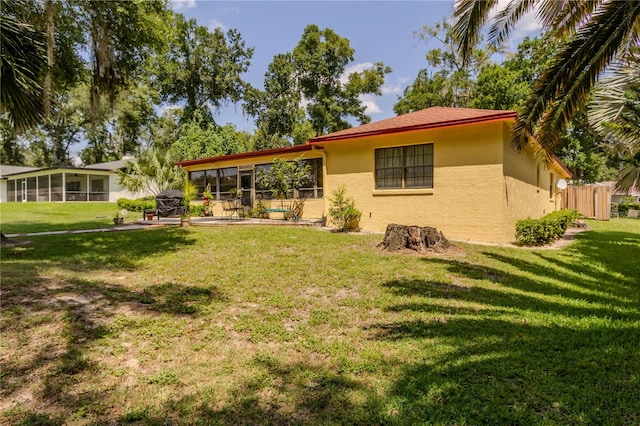 back of property with a sunroom and a yard