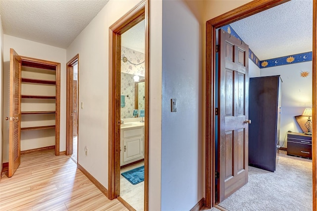 1546 Stormway Ct, Apopka, FL 32712 - hallway with a textured ceiling, light wood-style flooring, baseboards, and a sink
