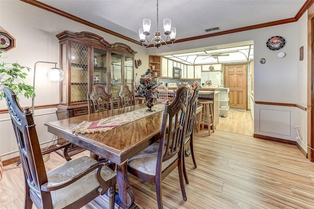 1546 Stormway Ct, Apopka, FL 32712 - dining room with a chandelier, light wood-style floors, crown molding, a textured ceiling, and a wainscoted wall