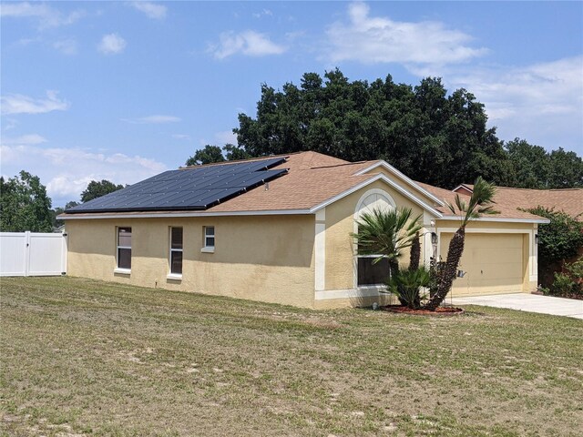 view of side of property with a garage, a yard, and solar panels