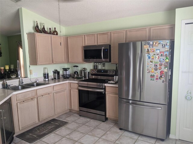 kitchen featuring appliances with stainless steel finishes, a textured ceiling, and light brown cabinets