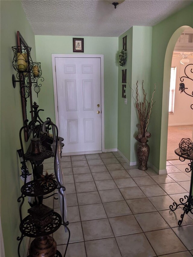 entryway with light tile patterned floors and a textured ceiling