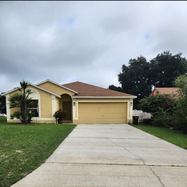 ranch-style house with a garage, a front yard, driveway, and stucco siding