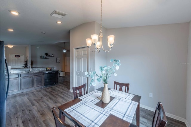 dining area with sink, a notable chandelier, vaulted ceiling, and wood-type flooring