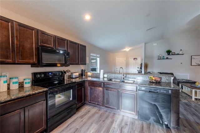 kitchen featuring lofted ceiling, dark brown cabinetry, a peninsula, a sink, and black appliances