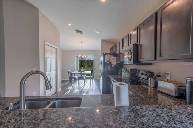 kitchen with dark stone countertops, visible vents, stainless steel appliances, and a sink