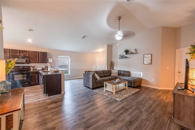 living area featuring vaulted ceiling, wood finished floors, visible vents, and a ceiling fan