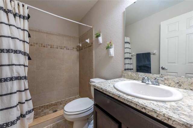 bathroom with toilet, vanity, curtained shower, and tile patterned floors