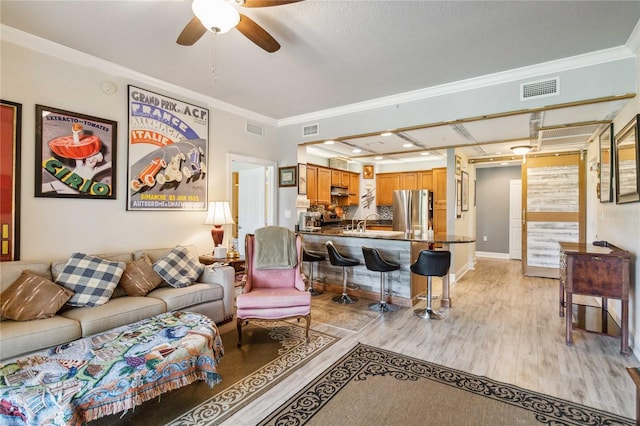 living room with ceiling fan, crown molding, and light hardwood / wood-style flooring