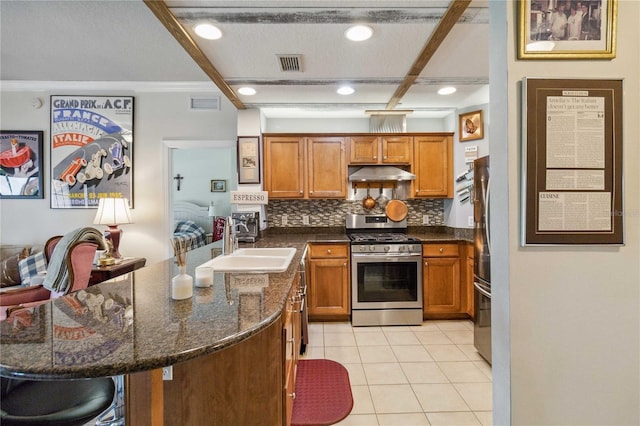 kitchen with decorative backsplash, a kitchen breakfast bar, appliances with stainless steel finishes, light tile patterned floors, and sink