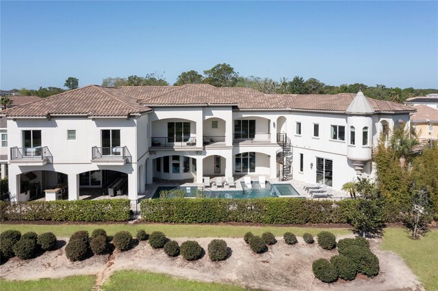 back of house with a balcony and a fenced in pool