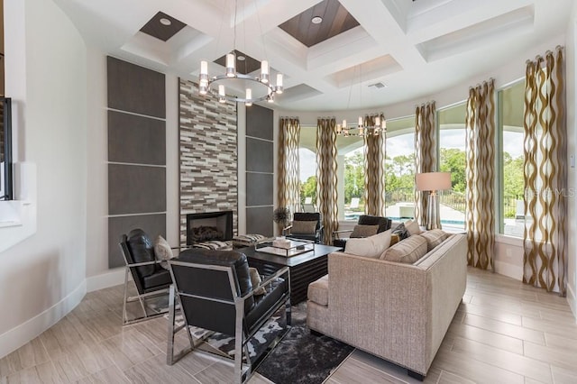 living room featuring beamed ceiling, a tiled fireplace, coffered ceiling, and an inviting chandelier