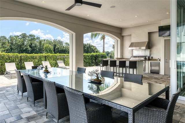 view of patio featuring ceiling fan, a bar, and exterior kitchen