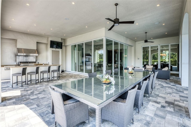 view of patio / terrace featuring ceiling fan, exterior kitchen, and a bar