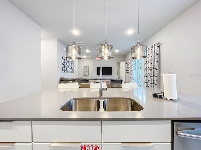 kitchen featuring a sink, visible vents, white cabinets, open floor plan, and pendant lighting