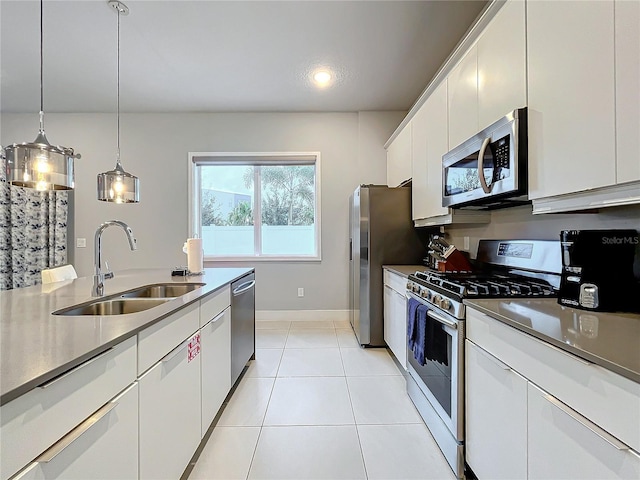 kitchen with pendant lighting, stainless steel appliances, light tile patterned flooring, sink, and white cabinets