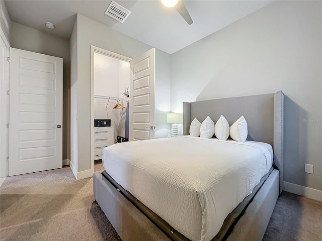 carpeted bedroom with a spacious closet, ceiling fan, and a closet