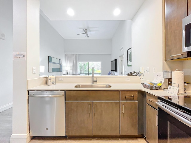 kitchen featuring appliances with stainless steel finishes, light countertops, a sink, and a ceiling fan