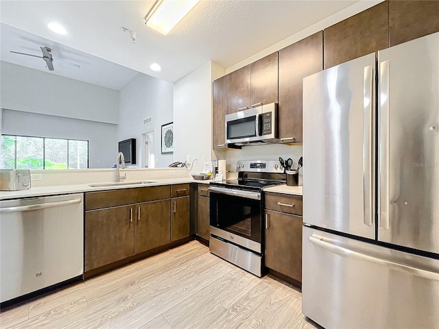 kitchen featuring stainless steel appliances, a sink, visible vents, light countertops, and light wood-type flooring