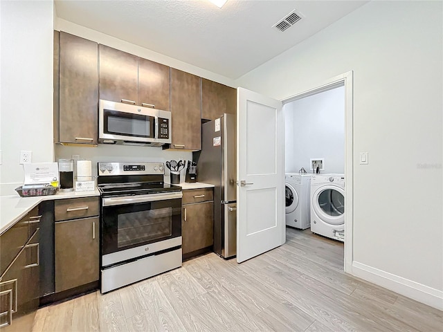 kitchen featuring visible vents, light countertops, appliances with stainless steel finishes, light wood finished floors, and washing machine and clothes dryer