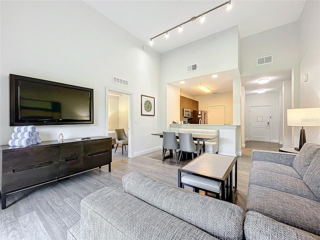 living room with baseboards, visible vents, and light wood-style floors