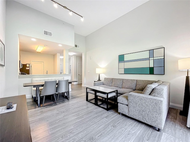 living room featuring high vaulted ceiling, visible vents, and light wood finished floors