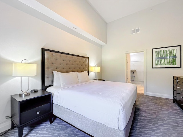 bedroom with high vaulted ceiling, connected bathroom, visible vents, baseboards, and dark colored carpet