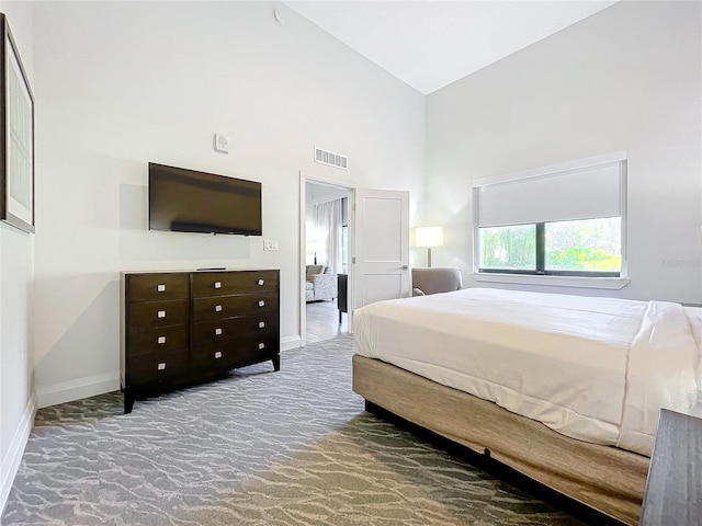 bedroom with carpet floors, a high ceiling, visible vents, and baseboards