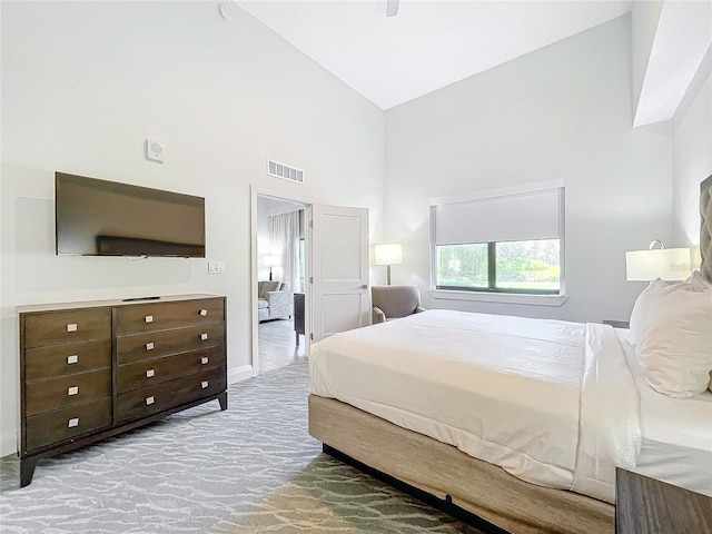 carpeted bedroom with high vaulted ceiling, visible vents, and baseboards