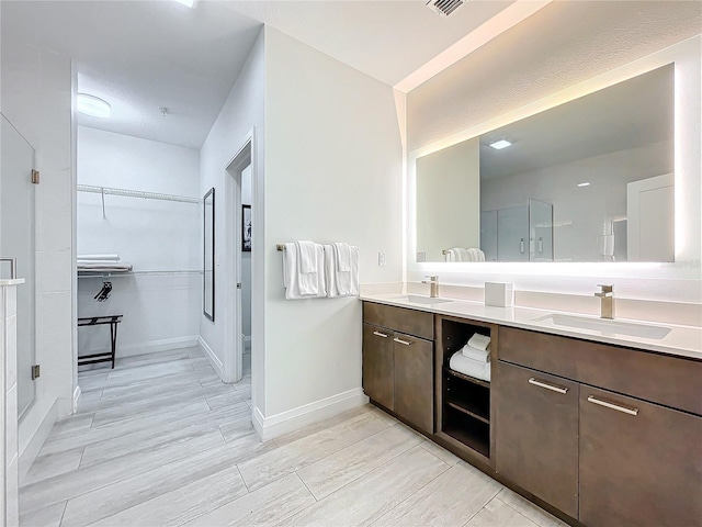 bathroom with a spacious closet, double vanity, a sink, and a shower stall