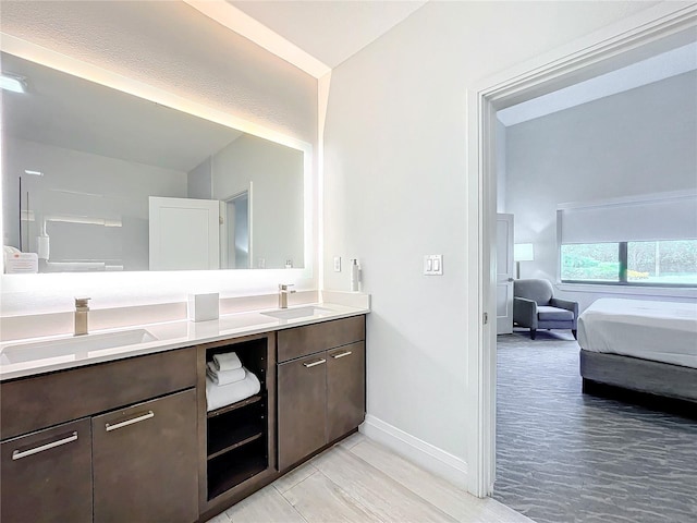 bathroom featuring double vanity, ensuite bath, baseboards, and a sink