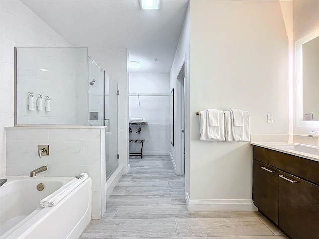 full bath with a stall shower, a spacious closet, wood finish floors, and vanity