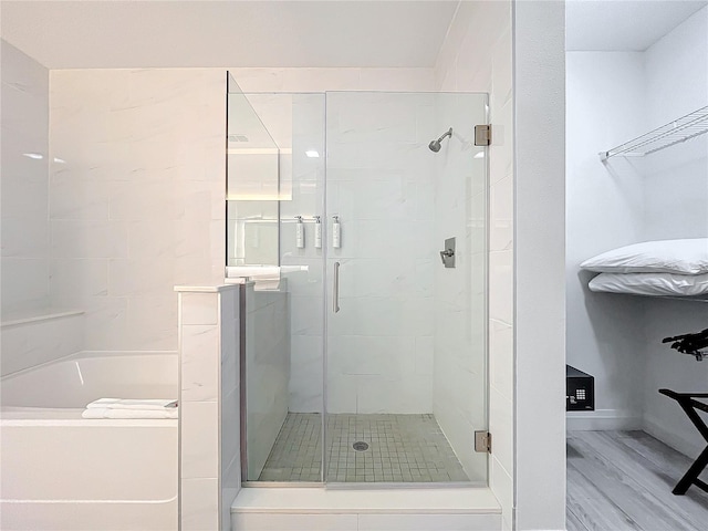 bathroom featuring a garden tub, a shower stall, a spacious closet, and baseboards