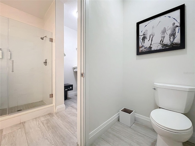 full bath featuring toilet, a stall shower, and baseboards