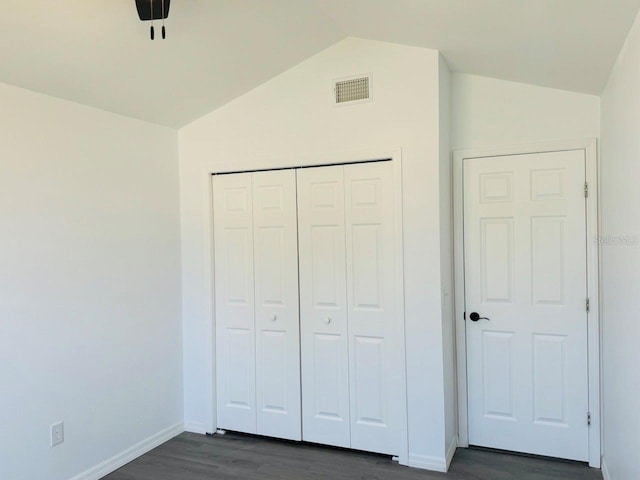 unfurnished bedroom with lofted ceiling, dark hardwood / wood-style floors, and a closet