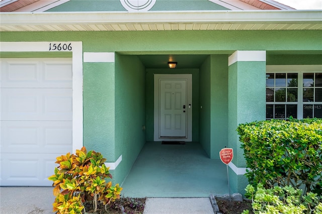 entrance to property with a garage and stucco siding