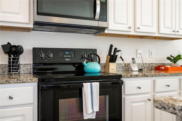 kitchen with black range with electric cooktop, light stone counters, stainless steel microwave, and white cabinets