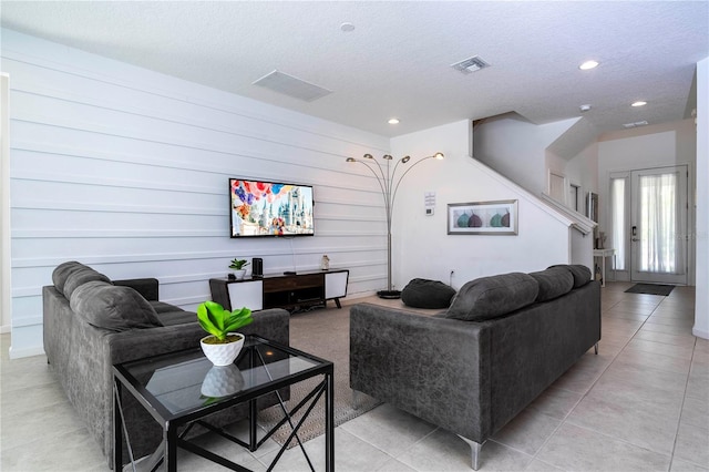 living room with a textured ceiling, light tile patterned flooring, visible vents, and recessed lighting