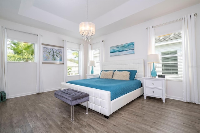 bedroom featuring a raised ceiling, hardwood / wood-style flooring, and a chandelier