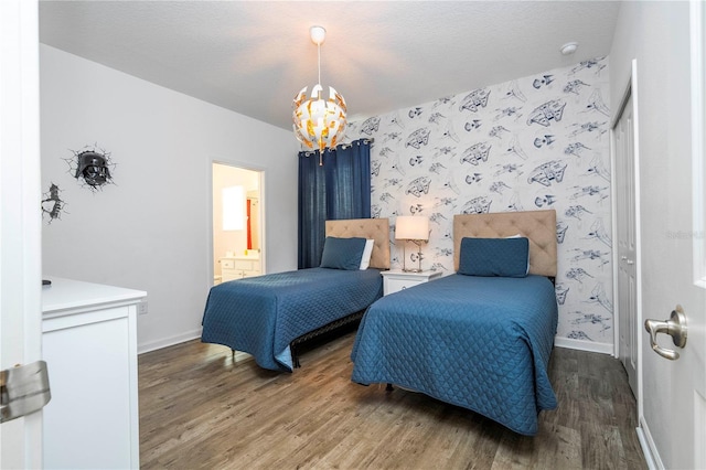 bedroom featuring wallpapered walls, baseboards, a chandelier, and wood finished floors