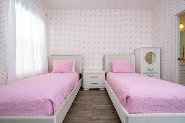 bedroom with wood finished floors, ensuite bathroom, and wallpapered walls