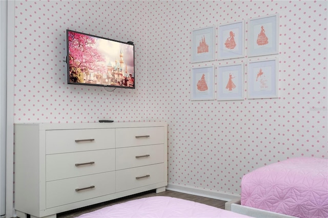 bedroom with wood finished floors, baseboards, and wallpapered walls