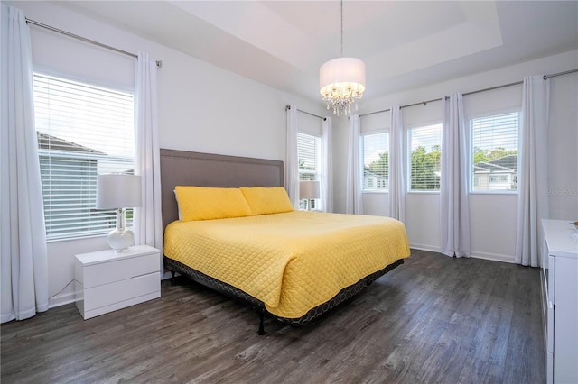 bedroom featuring an inviting chandelier, baseboards, a raised ceiling, and dark wood-type flooring