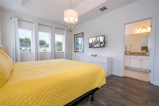 bedroom featuring hardwood / wood-style flooring, an inviting chandelier, and ensuite bathroom