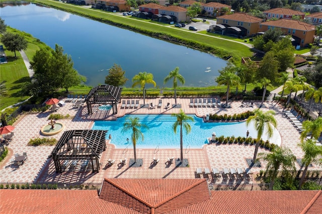 community pool featuring a water view, fence, and a patio