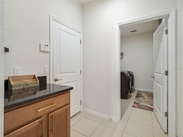 bathroom featuring baseboards, visible vents, washer and clothes dryer, and tile patterned floors